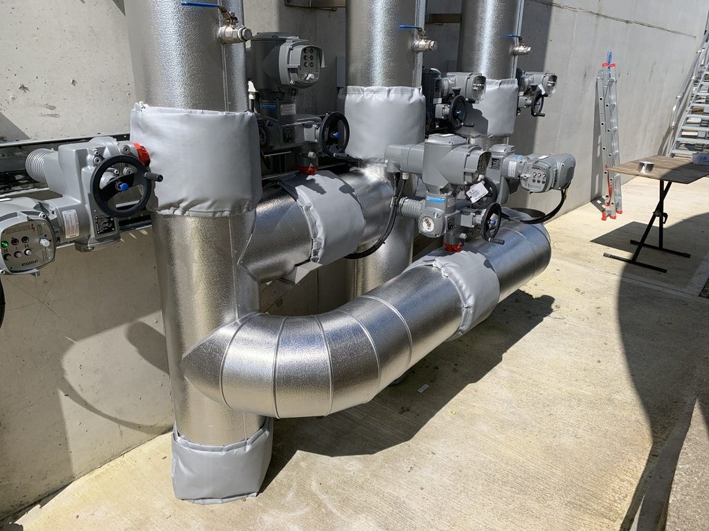 Outdoor insulated pipework with metal cladding and removable jackets at valves