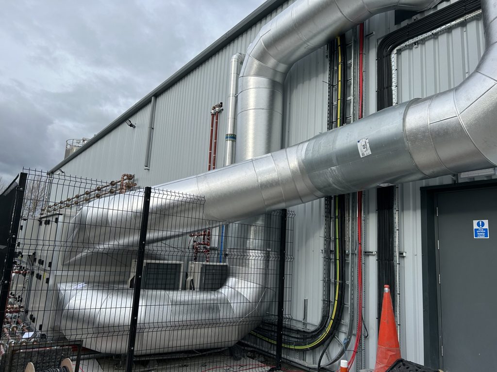 Metal-clad external services with formed bends along an industrial building
