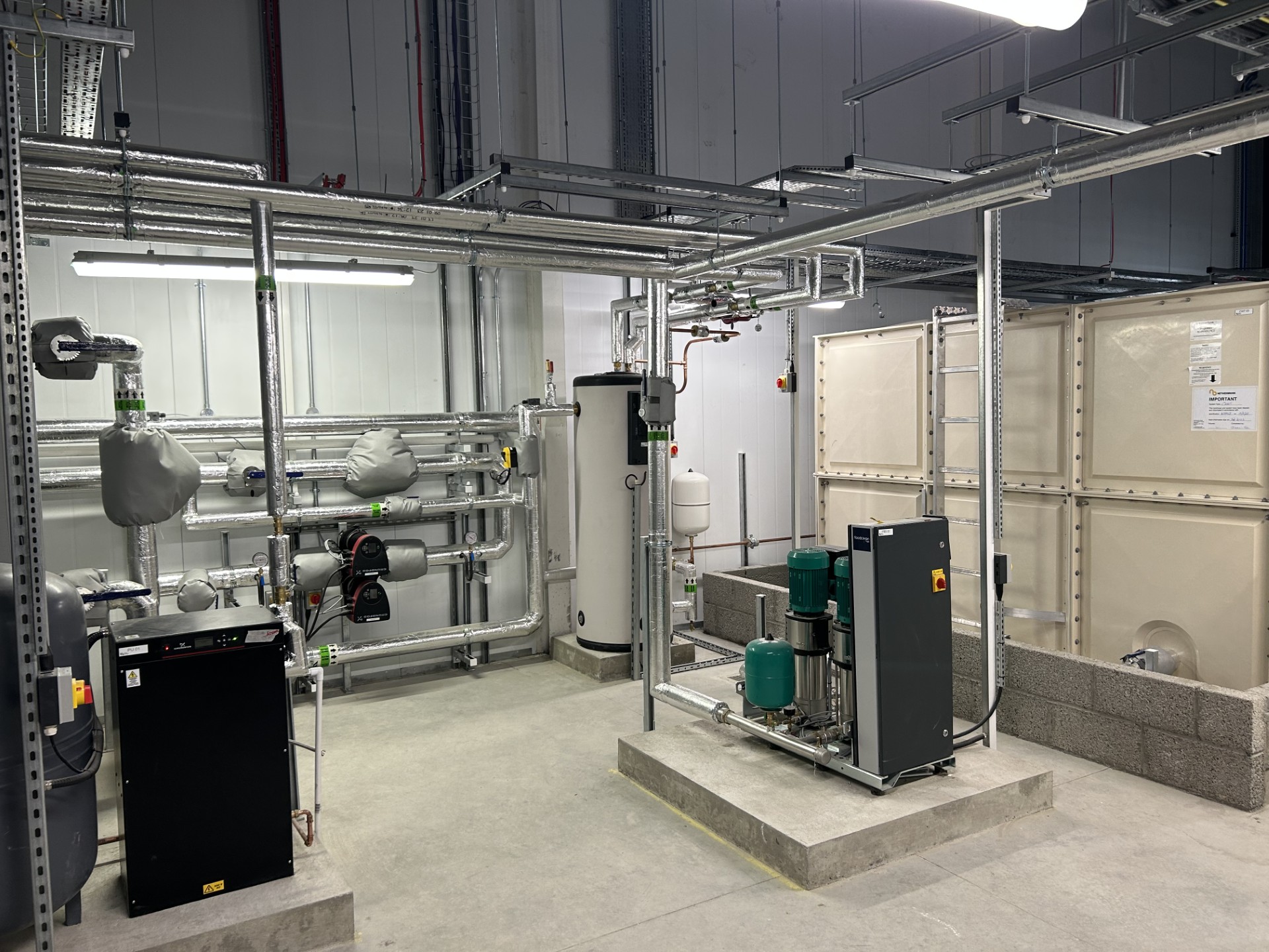Insulated distribution pipework and removable covers around the plant-room vessel, shown from a wider finished angle.