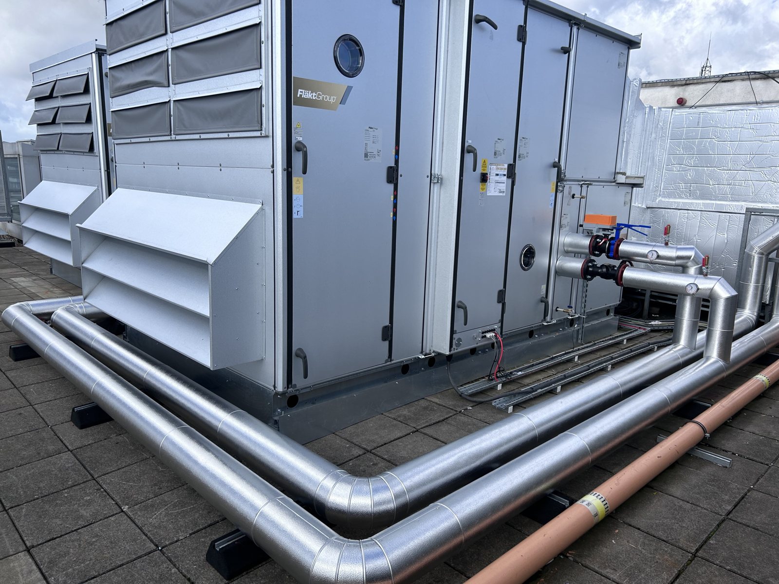 Fibreglass insulation and stucco aluminium cladding installed on rooftop AHU pipework services.