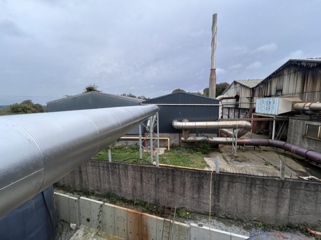 Long external run of aluminium-clad boiler flue across a metal recycling facility, Co. Meath
