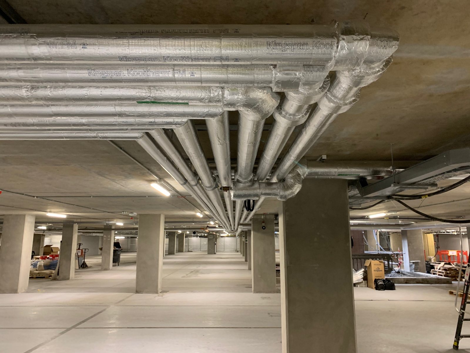Foil-faced insulation following overhead pipe runs and changes of direction.
