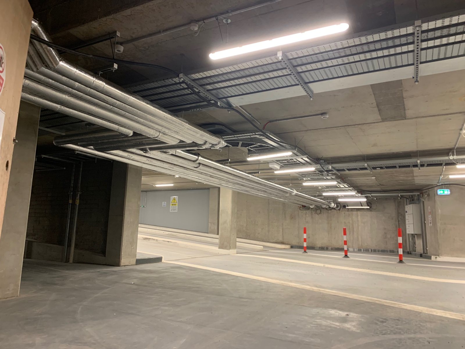 Overhead insulated pipework distributed through an underground building services area.