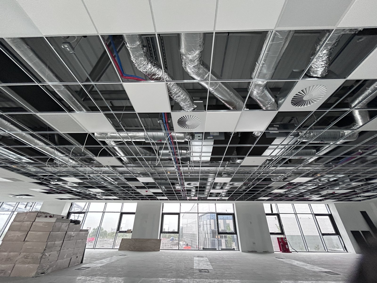 Insulated ventilation ductwork above a suspended ceiling grid.