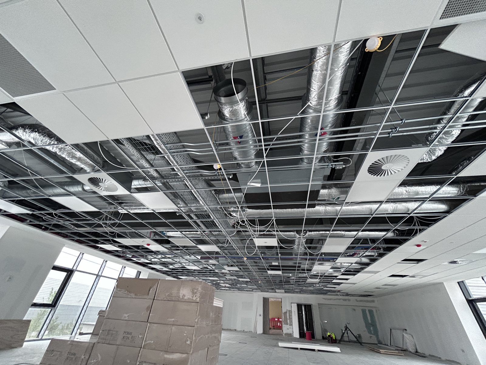 Insulated services distributed above a ceiling grid during building works.