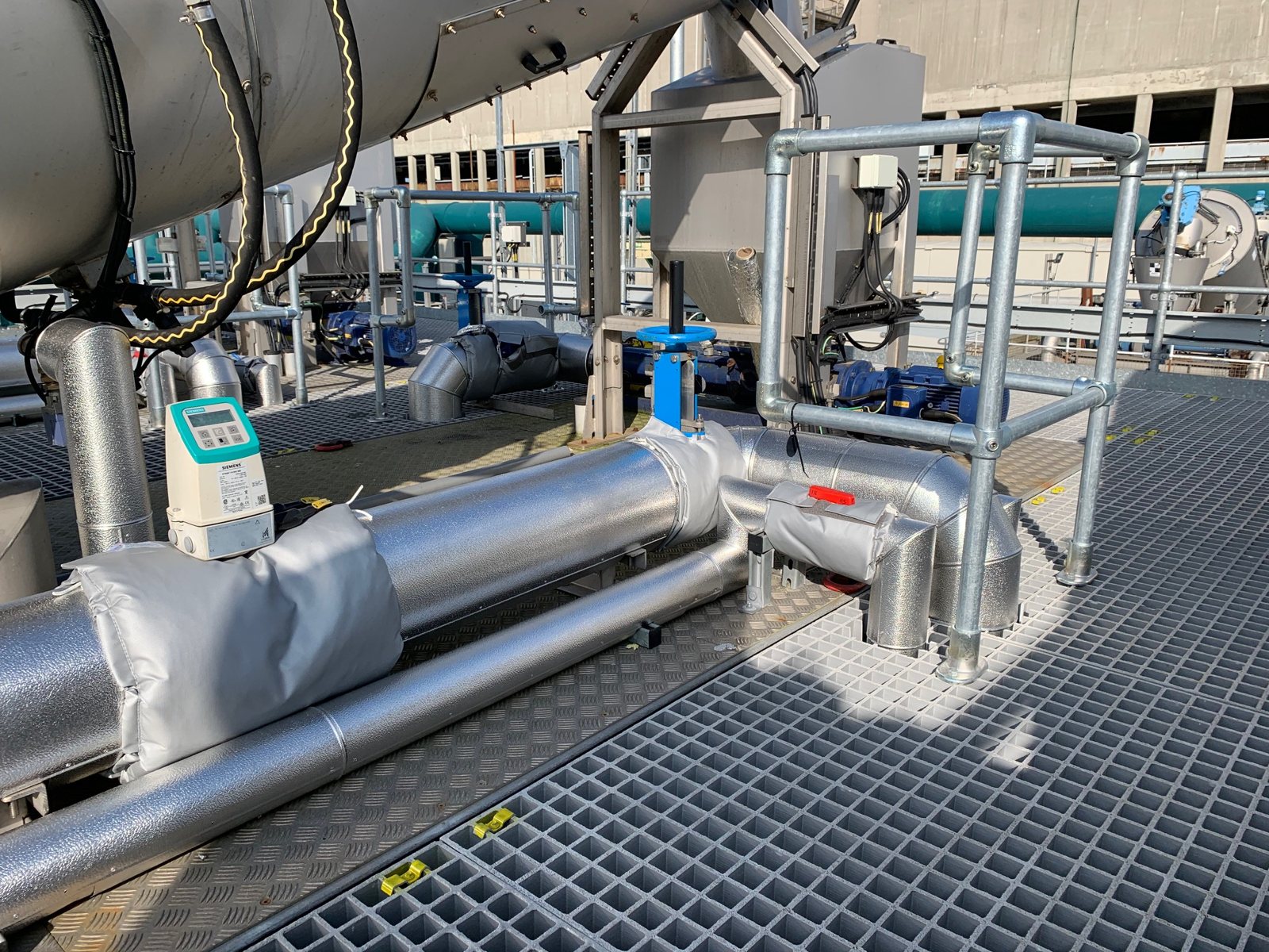 Clad distribution pipework beneath external mechanical plant.