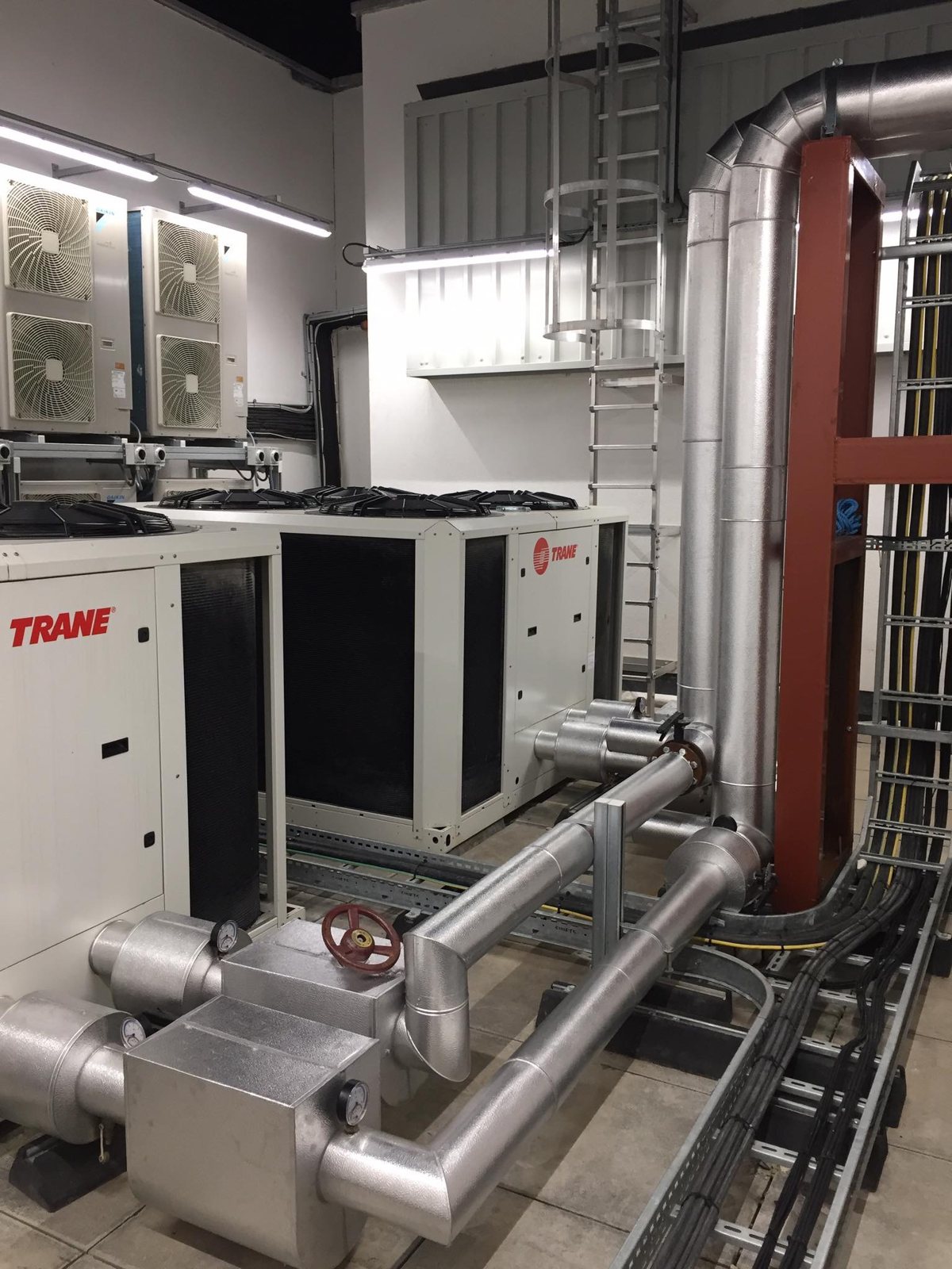 Metal-clad insulation on pipework beside external chiller plant.