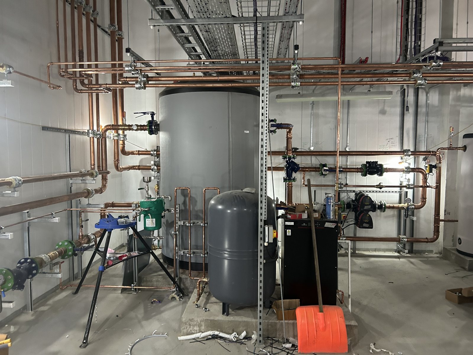 Before insulation: exposed copper distribution pipework around a plant-room vessel.