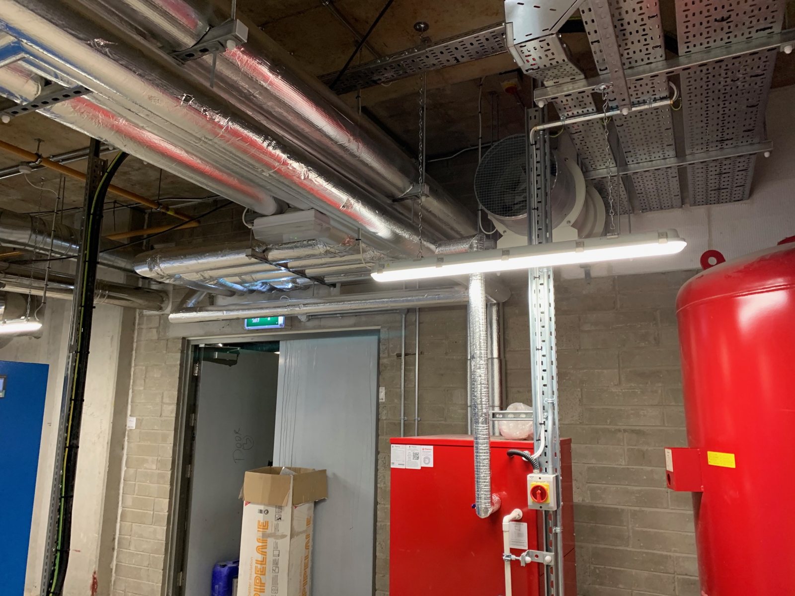Insulated high-level pipework and service connections in a plant room.