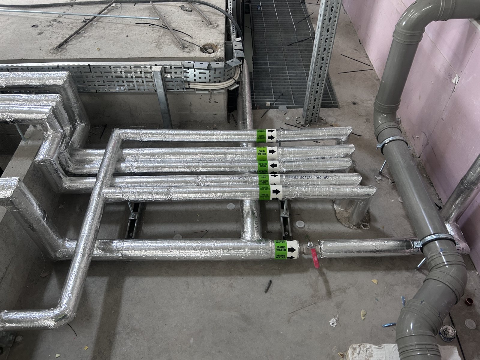 Foil-faced insulation on low-level distribution pipework and branches.