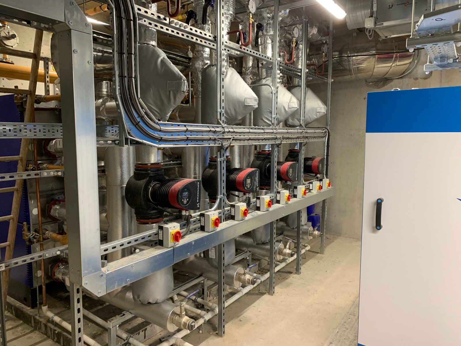 Insulated pipework arranged around a bank of circulation pumps.