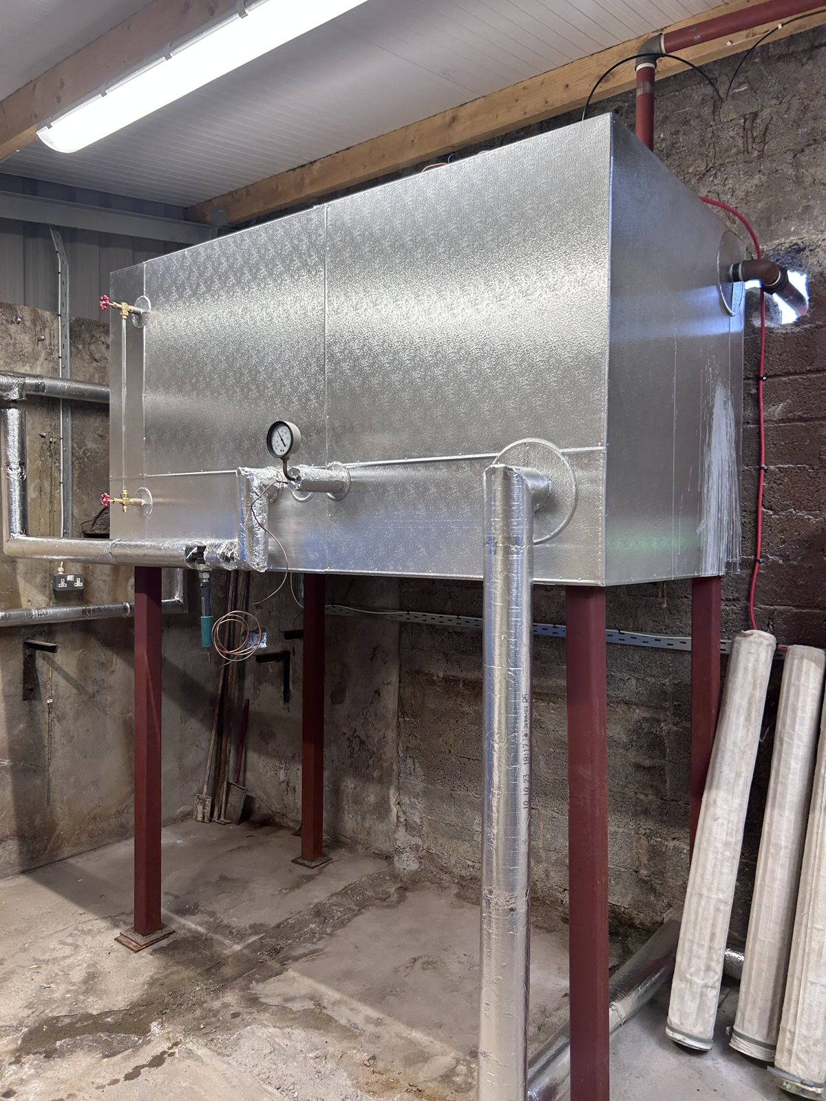 Fabricated metal cladding around a rectangular tank and its connections.