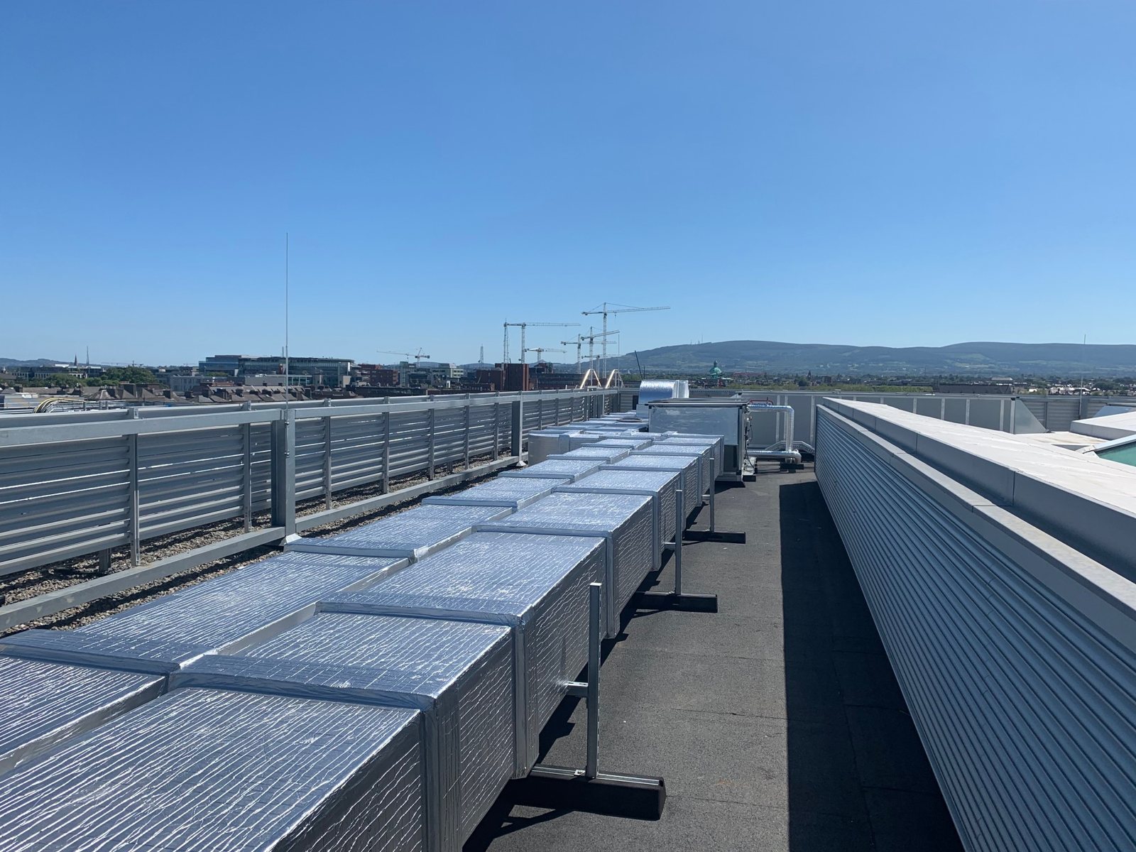 A long run of rectangular roof-level ductwork with protective metal cladding.