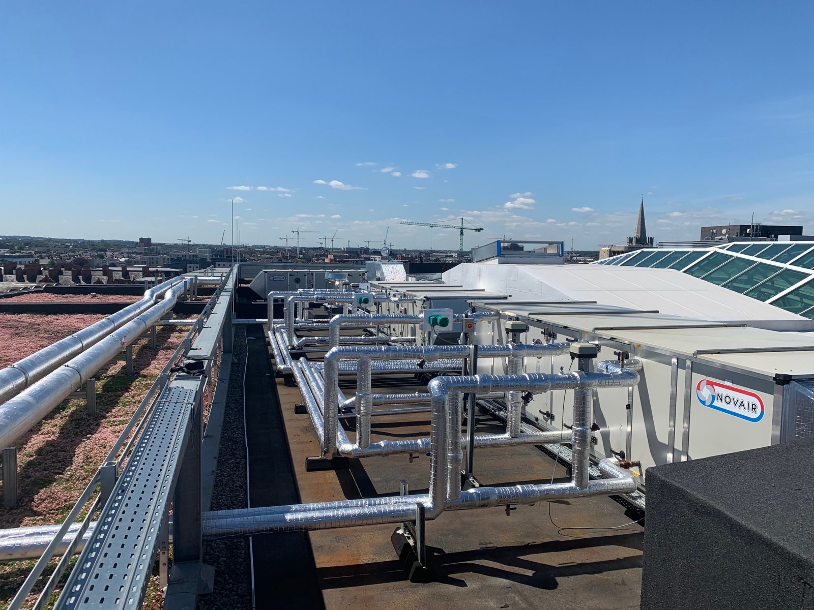 Insulated and clad pipework routed between rooftop mechanical plant.