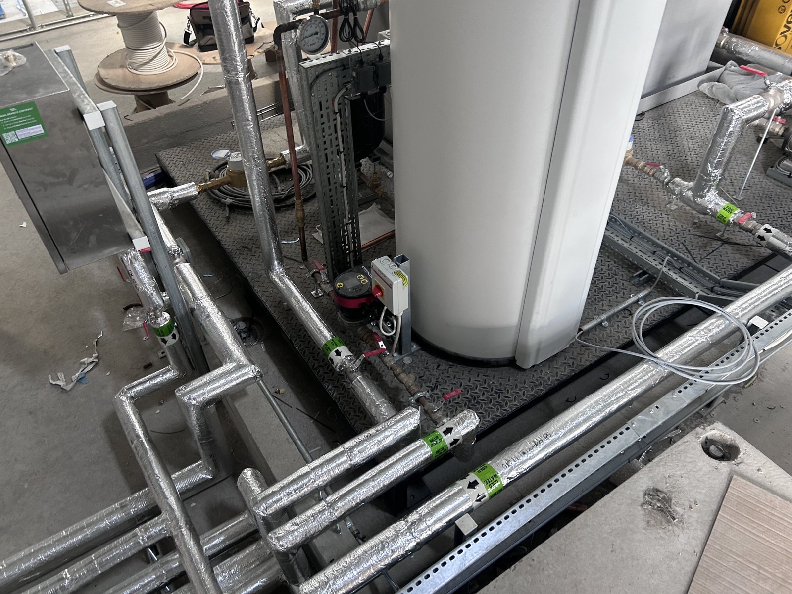 Insulated pipework and service connections arranged around a storage vessel.